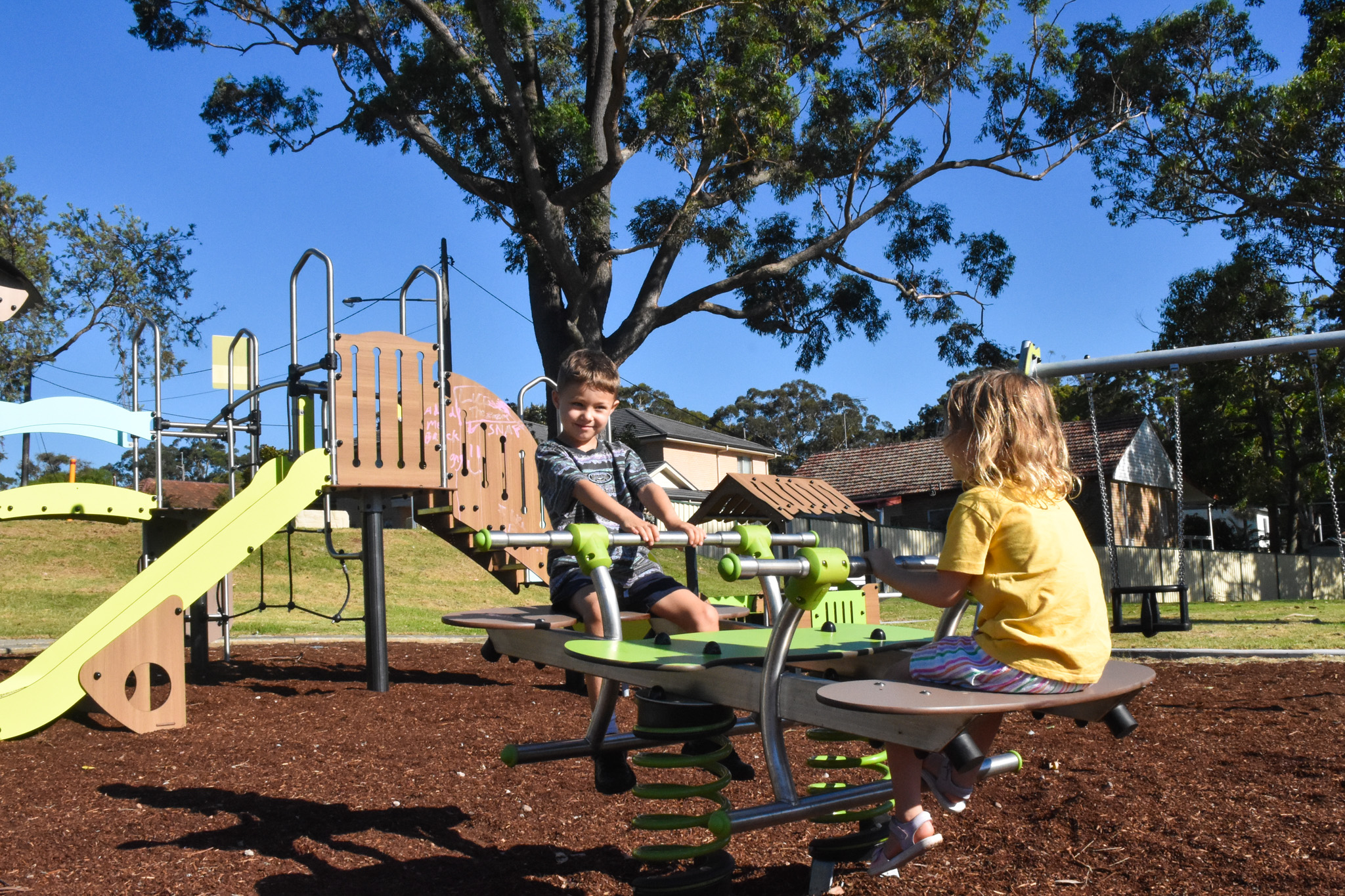 Two children seated on a see-saw at an outdoor playground