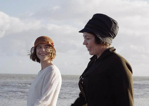 Still from film Wicked Little Letters. Two women in period costume walking along a beach.