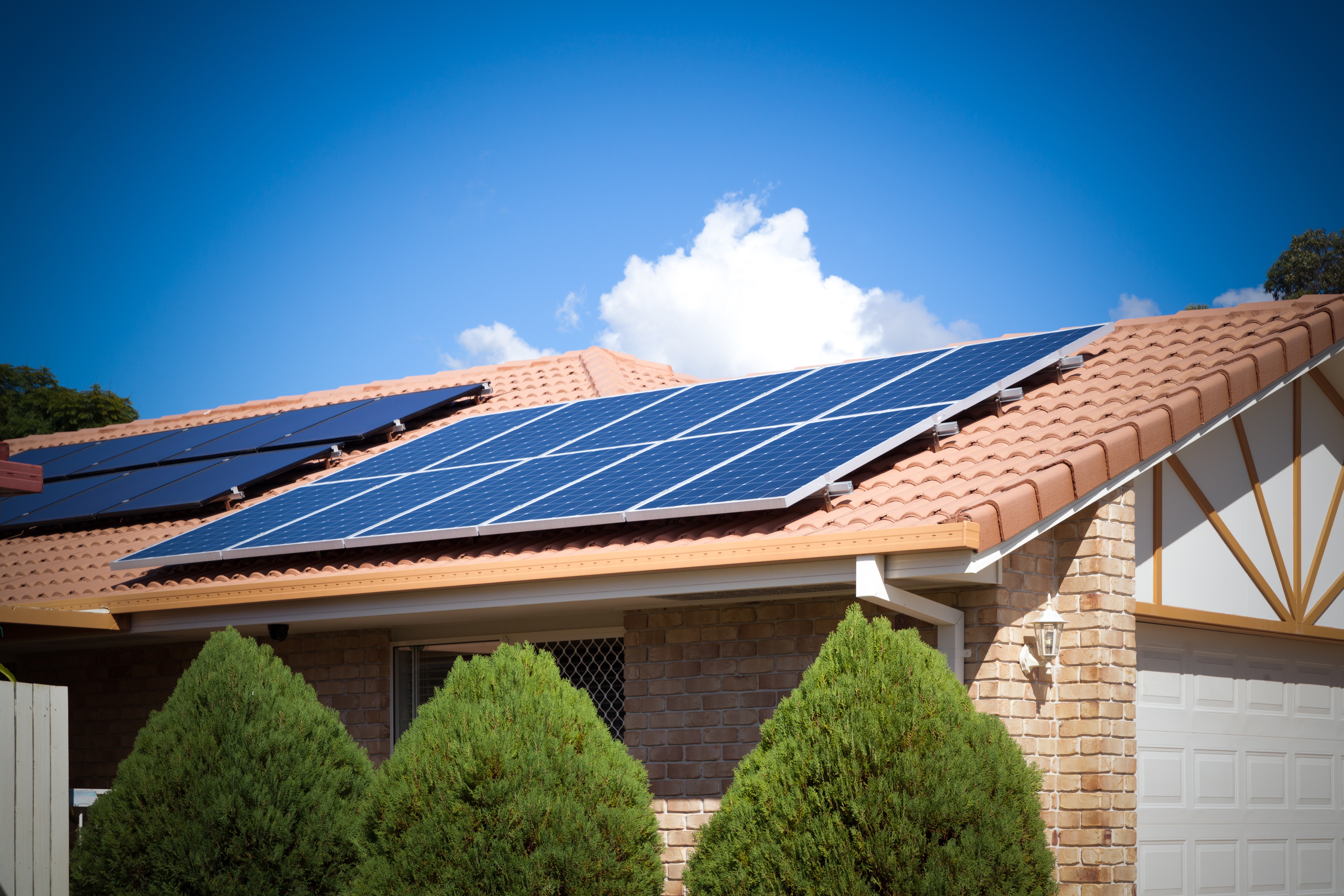 image of suburban house with solar panels under sunny sky