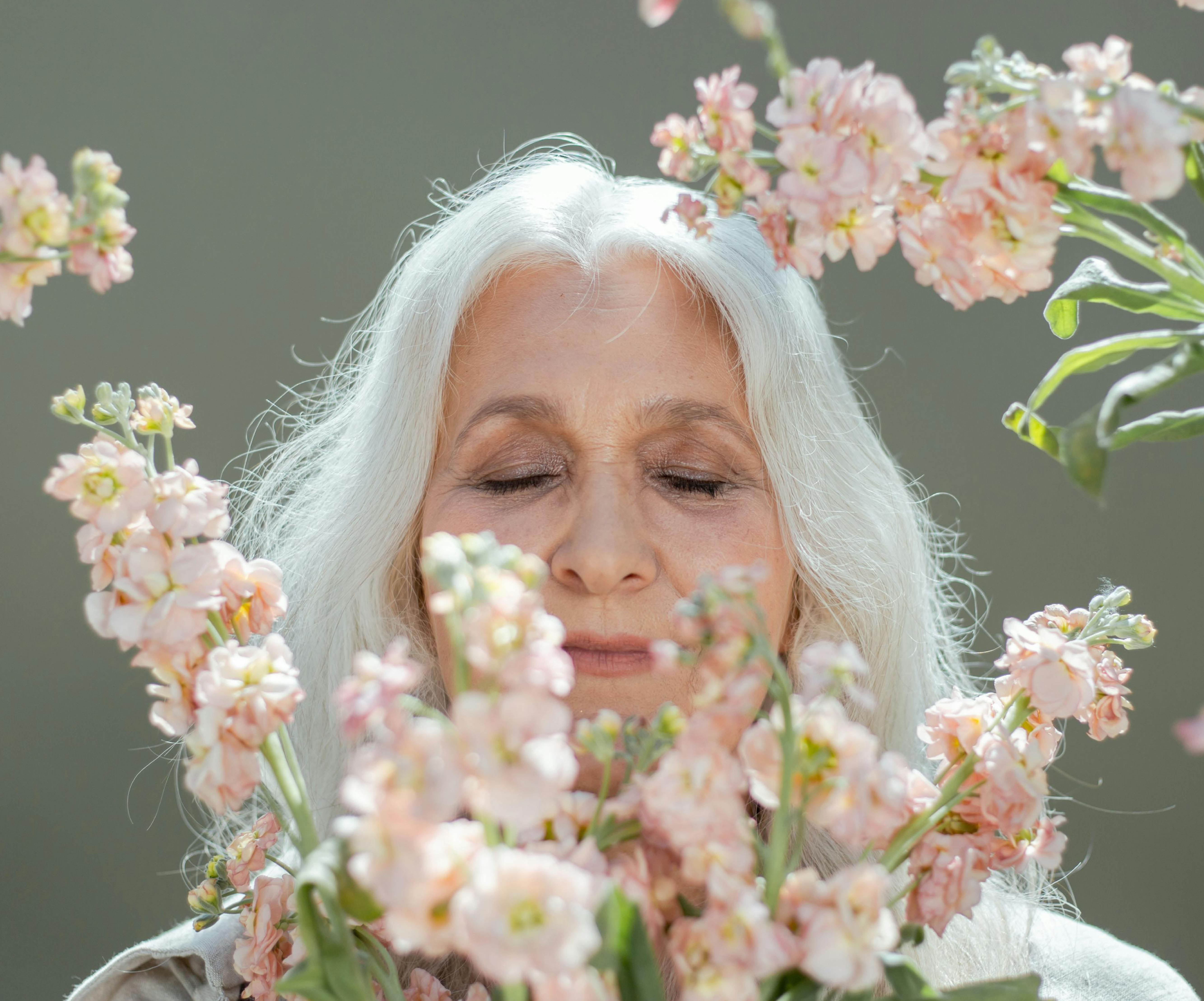 senior woman smelling flowers with her eyes closed