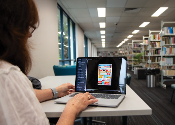 Woman works on a laptop while sitting in the library