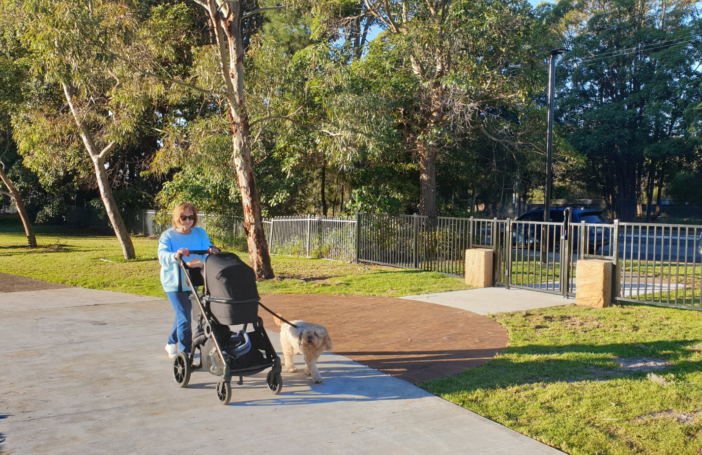 Lady and stroller on wide walking path near entry gate