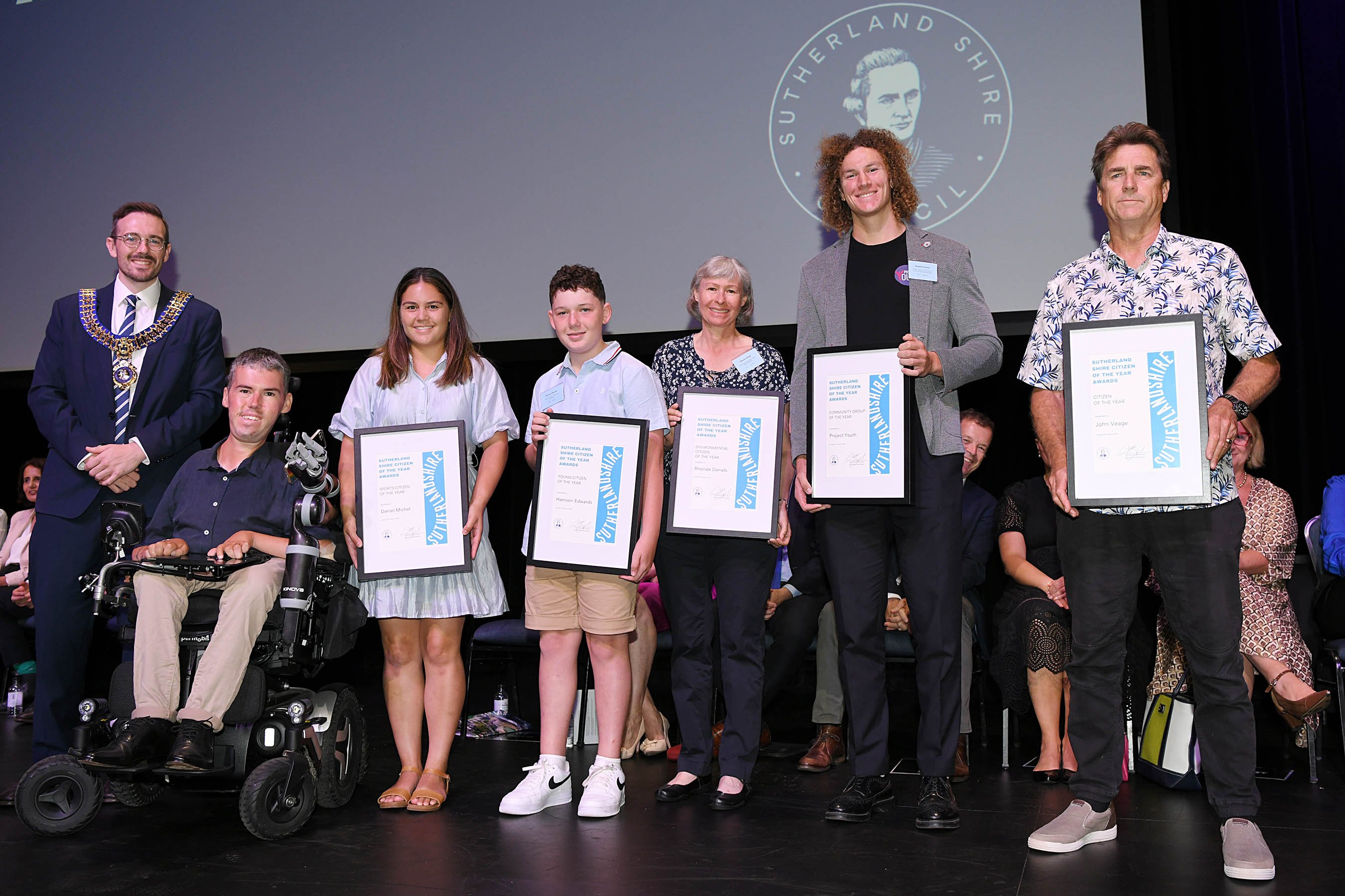 Sutherland Shire Mayor Clr Jack Boyd standing with the 2025 Sutherland Shire Citizen of the Year Award winners on a stage at the Pavilion Performing Arts Centre