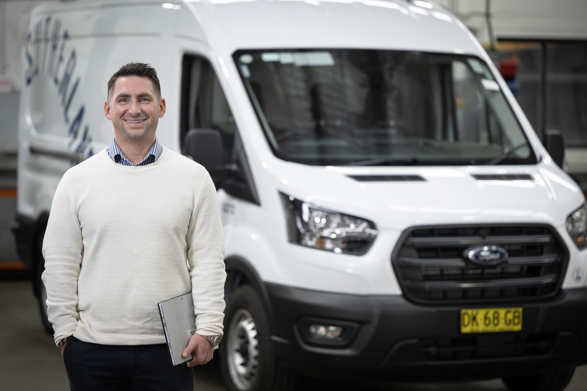 Man standing with a laptop computer in hand with a white council branded vehicle in the background