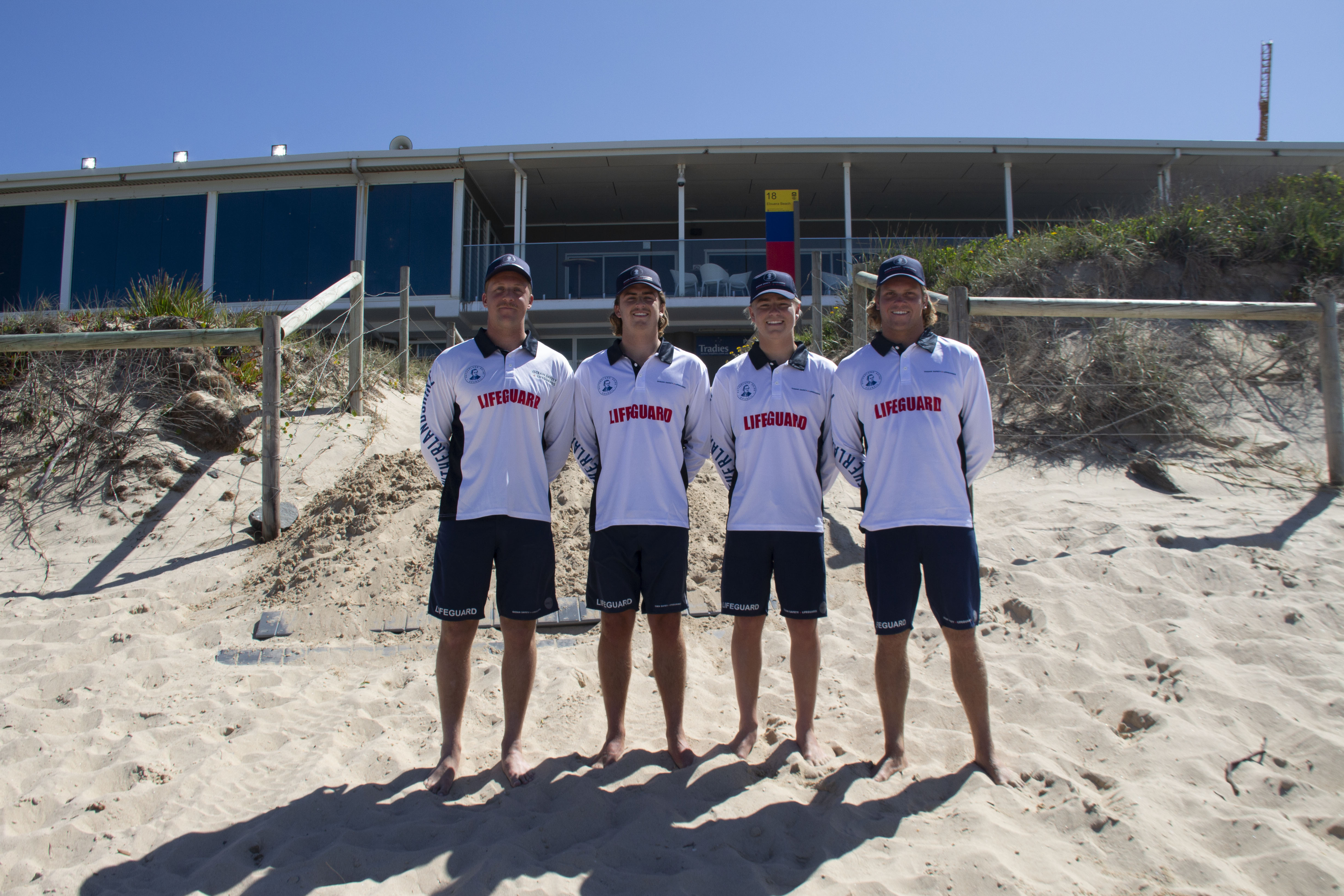 A group of four lifeguards standing out the front on the beach of Elouera Surf Life Saving Club