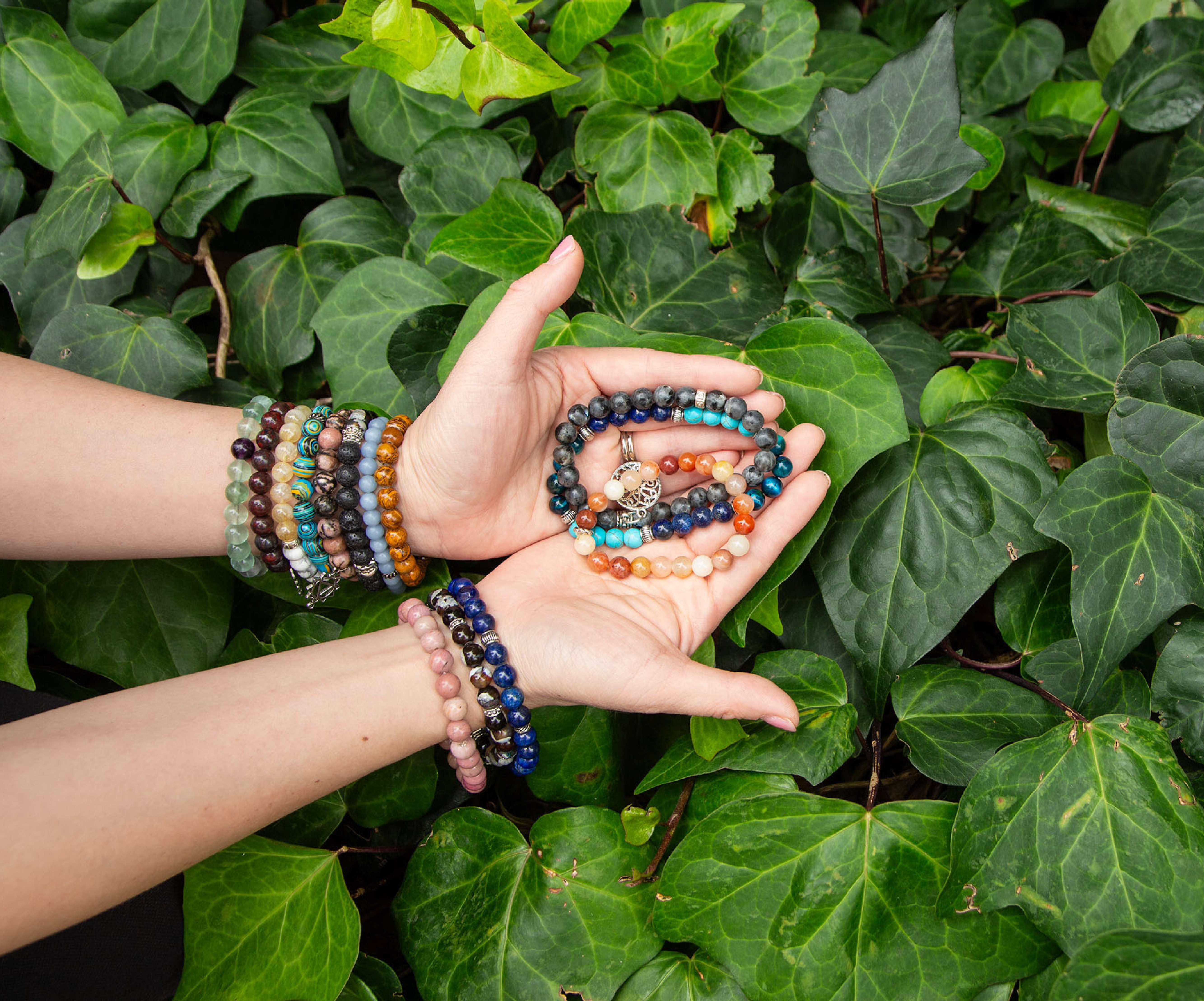 hands holding gemstone bracelets