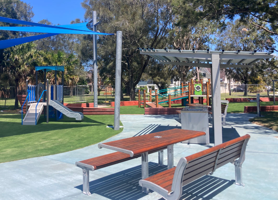 Table and seats with BBQ and Playground in the background