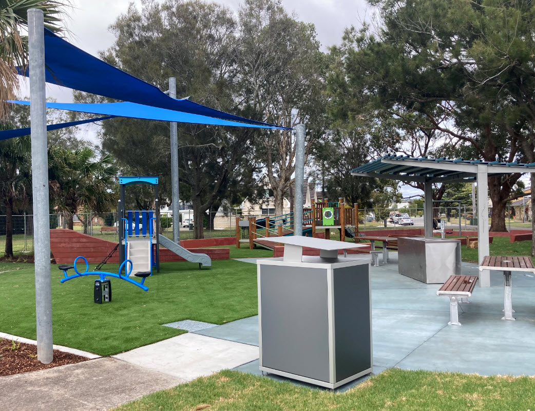 Bin with seating and Playground equipment under blue shade sail