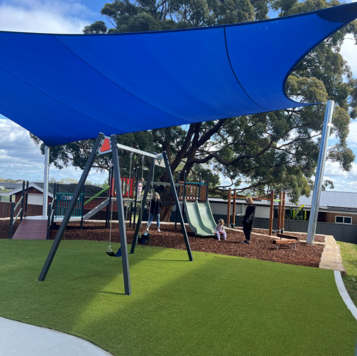 New synthetic turf and play equipment under blue shade sail