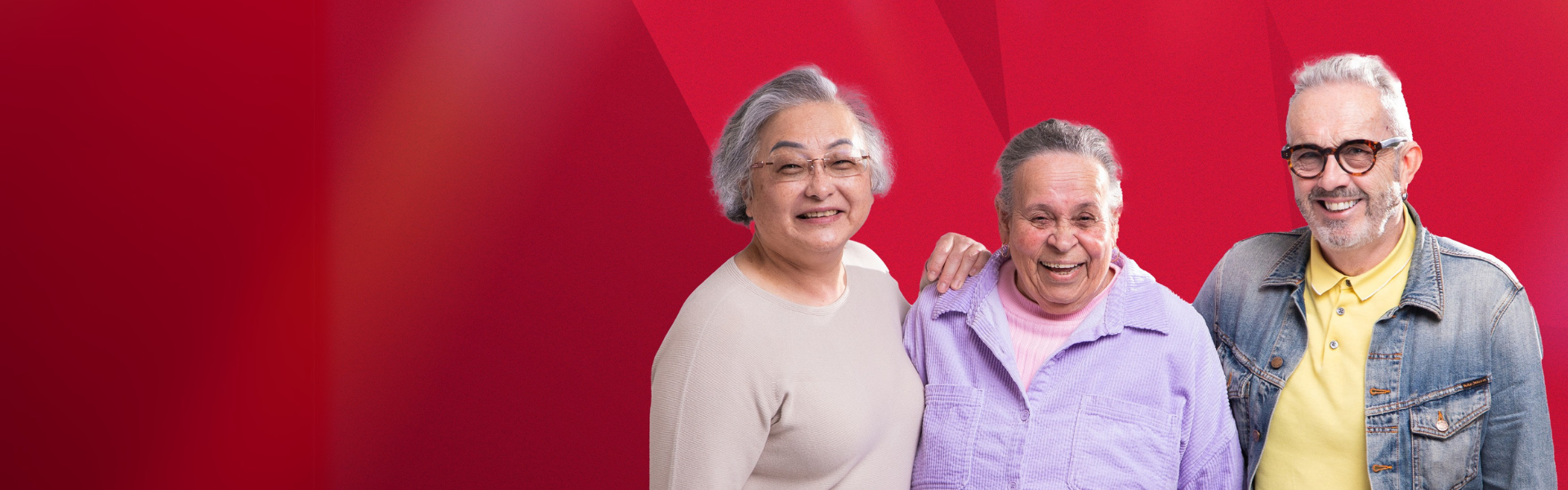 three older people hugging and smiling at camera