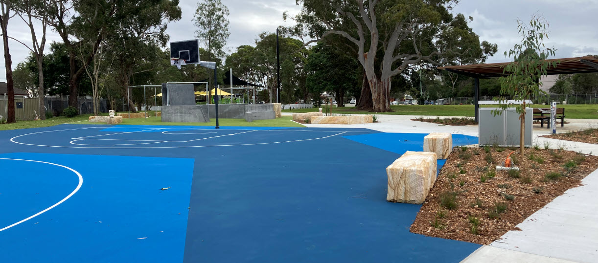 Blue court surface and bins with open parkland in distance