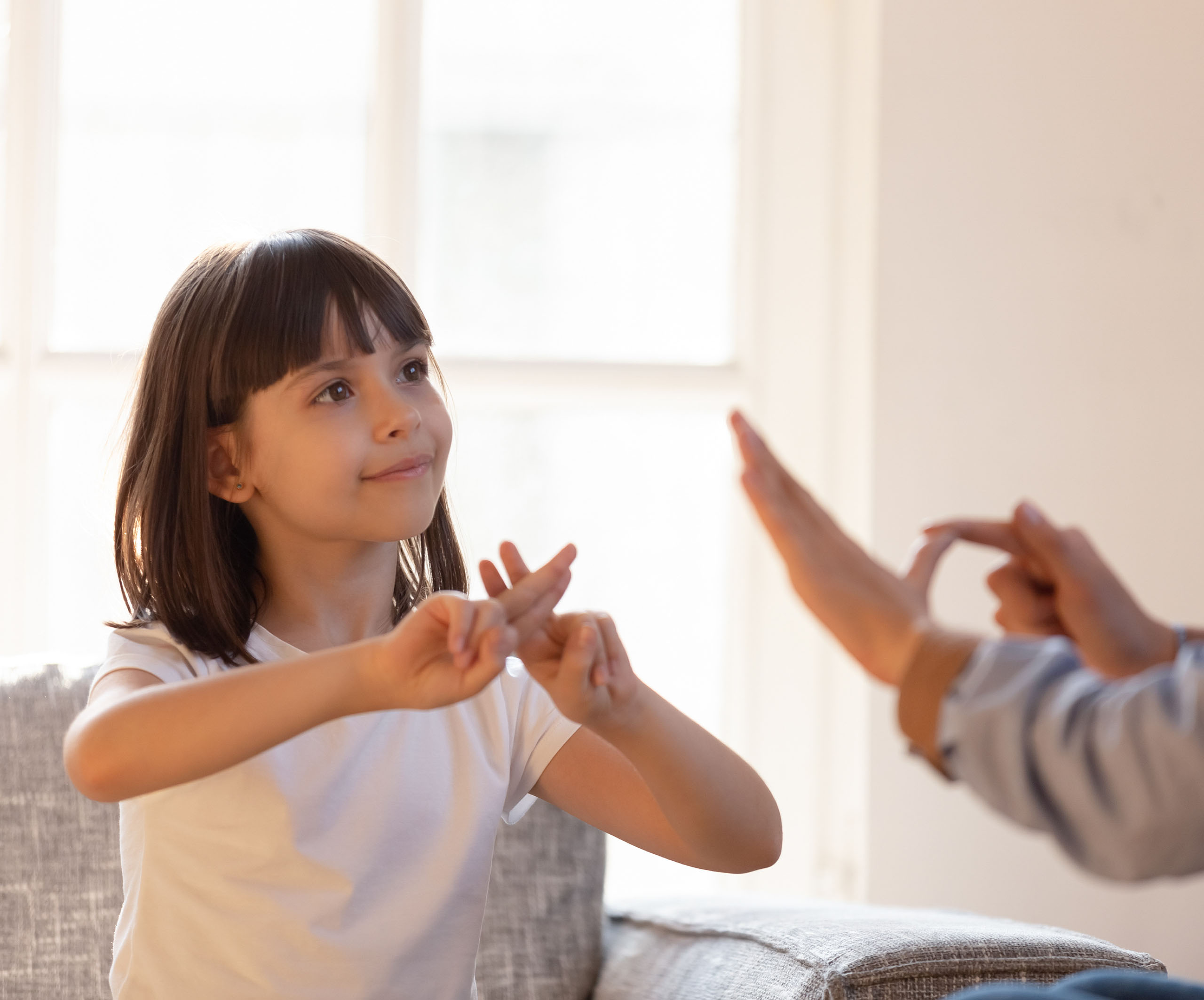 young girl doing sign language to parent