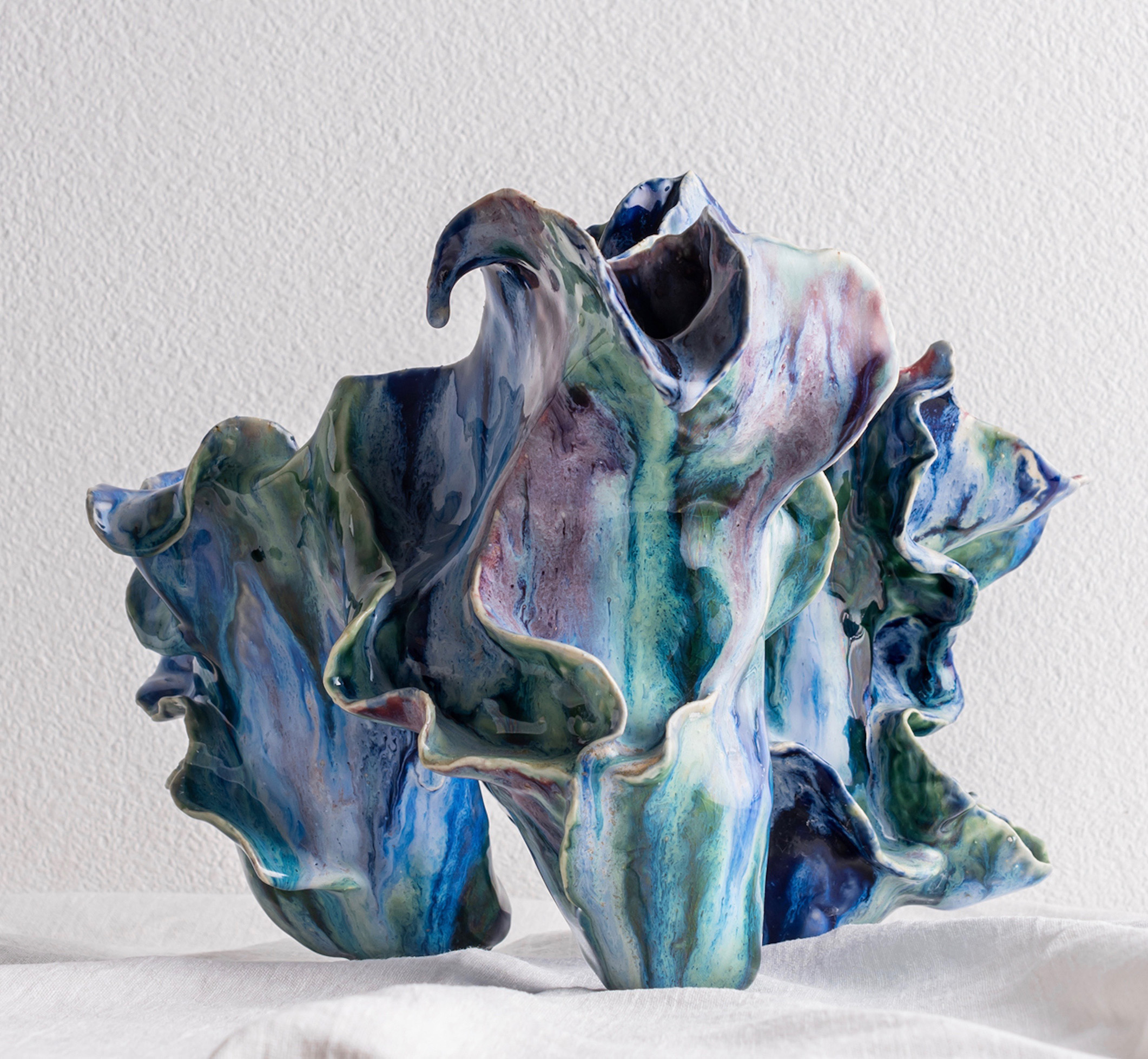 A series of organic, flowing ceramic forms glazed it washes of greens, pinks and blues.