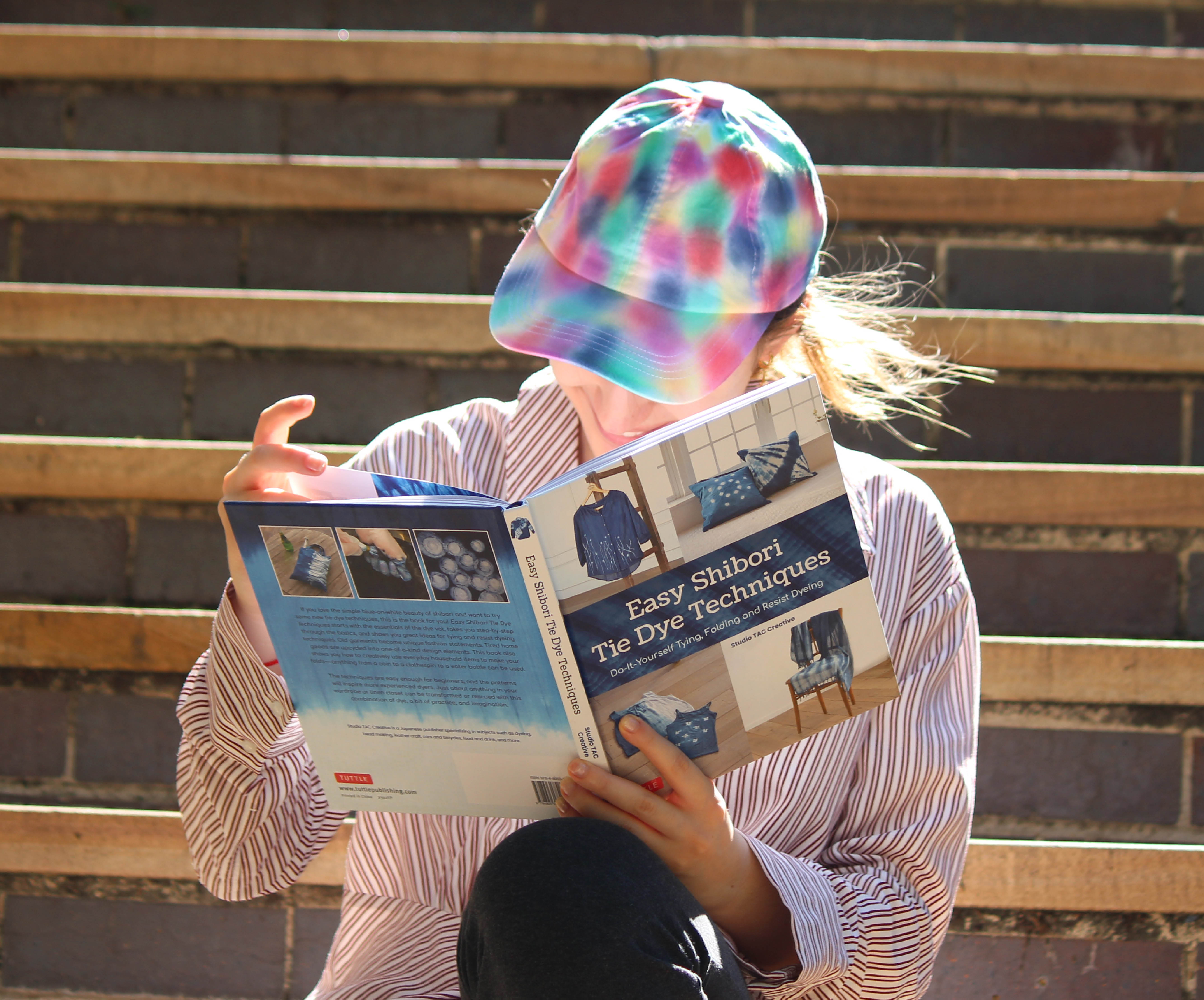 Young woman reading book wearing tie dyed cap