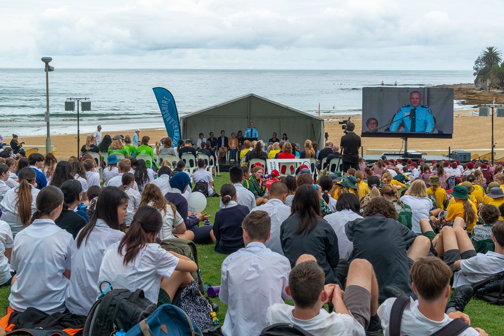 Group of students watching presentations on stage at Cronulla Park